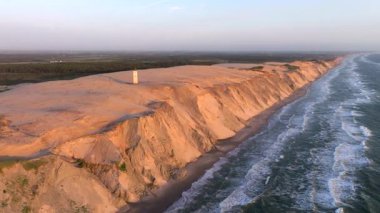 Tepenin tepesinde ünlü deniz feneri olan dev kum tepelerinin hava manzarası. Rubjerg Knude Deniz Feneri, Kuzey Deniz Rubjerg, Danimarka Lokken yakınlarındaki Rubjerg Knude Fyr deniz fenerinde gün batımı. 