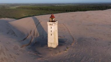 Tepenin tepesinde ünlü deniz feneri olan dev kum tepelerinin hava manzarası. Rubjerg Knude Deniz Feneri, Kuzey Deniz Rubjerg, Danimarka Lokken yakınlarındaki Rubjerg Knude Fyr deniz fenerinde gün batımı. 
