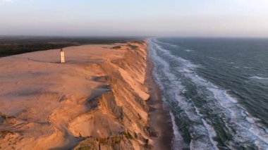 Tepenin tepesinde ünlü deniz feneri olan dev kum tepelerinin hava manzarası. Rubjerg Knude Deniz Feneri, Kuzey Deniz Rubjerg, Danimarka Lokken yakınlarındaki Rubjerg Knude Fyr deniz fenerinde gün batımı. 