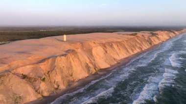 Tepenin tepesinde ünlü deniz feneri olan dev kum tepelerinin hava manzarası. Rubjerg Knude Deniz Feneri, Kuzey Deniz Rubjerg, Danimarka Lokken yakınlarındaki Rubjerg Knude Fyr deniz fenerinde gün batımı. 