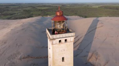 Tepenin tepesinde ünlü deniz feneri olan dev kum tepelerinin hava manzarası. Rubjerg Knude Deniz Feneri, Kuzey Deniz Rubjerg, Danimarka Lokken yakınlarındaki Rubjerg Knude Fyr deniz fenerinde gün batımı. 