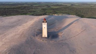 Tepenin tepesinde ünlü deniz feneri olan dev kum tepelerinin hava manzarası. Rubjerg Knude Deniz Feneri, Kuzey Deniz Rubjerg, Danimarka Lokken yakınlarındaki Rubjerg Knude Fyr deniz fenerinde gün batımı. 