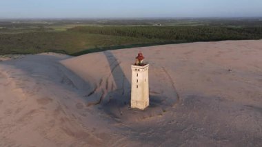 Tepenin tepesinde ünlü deniz feneri olan dev kum tepelerinin hava manzarası. Rubjerg Knude Deniz Feneri, Kuzey Deniz Rubjerg, Danimarka Lokken yakınlarındaki Rubjerg Knude Fyr deniz fenerinde gün batımı. 