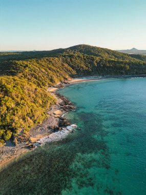 Okyanusa bakan mavi gökyüzü bulutsuz gününde Noosa Ulusal Parkı Queensland Avustralya üzerindeki hava görüntüleri. Yüksek Kalite Video