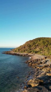 Okyanusa bakan mavi gökyüzü bulutsuz gününde Noosa Ulusal Parkı Queensland Avustralya üzerindeki hava görüntüleri. Yüksek Kalite Video