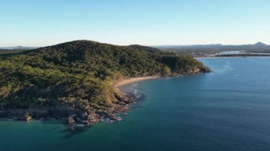 Okyanusa bakan mavi gökyüzü bulutsuz gününde Noosa Ulusal Parkı Queensland Avustralya üzerindeki hava görüntüleri. Yüksek Kalite Video