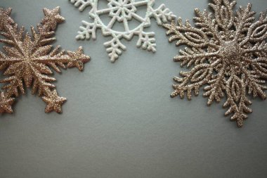 Gri arka planda beyaz, altın, gümüş ve bronz kar taneleri, Noel süslemeleri