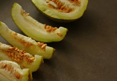 Küçük karpuz, tarla mahsulü koyu bir arka planda dilimler halinde kesilmiş.