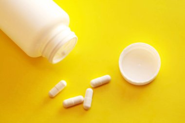 Sarı arka planda beyaz vitaminler.