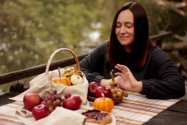 Gölde piknik, şapkalı genç bir kadın, elinde bir bardak şarap.