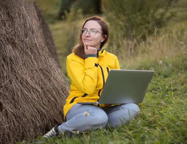 girl works at the laptop in nature, thoughtful