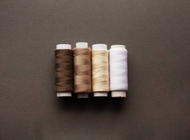 Gri bir kumaşın üzerinde renkli dikiş iplikleri, üst görünüm