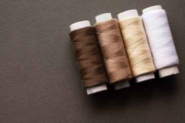 Gri bir kumaşın üzerinde renkli dikiş iplikleri, üst görünüm