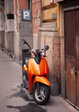 Turuncu bir motosiklet sokakta duruyor.