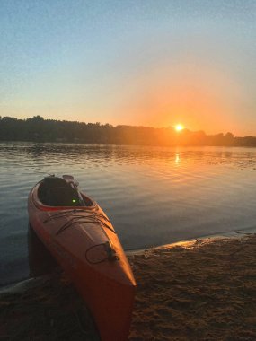 Gün batımında deniz kenarında kano.