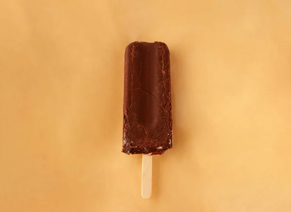 chocolate ice cream on a stick on a light peach fuzz background