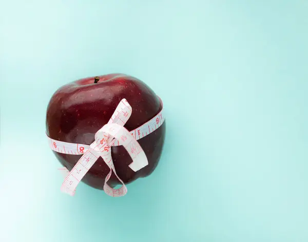diet concept, an apple with centimeter tape