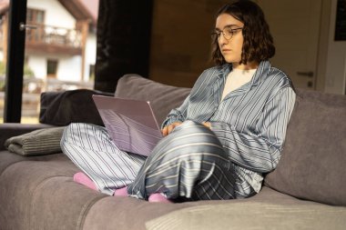 Kanepedeki kız bilgisayarda çalışıyor, serbest çalışıyor, evde çalışıyor.