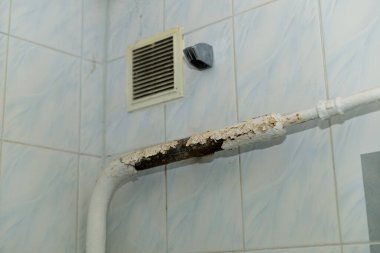 Banyodaki boruda beyaz boya çatlamış, pas tutmuş.