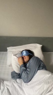 Yatakta uyuyan maskeli genç bir kadın uyuyor ve kafasını bir boşlukla örtüyor.