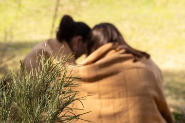 Ormanda battaniyenin altında iki genç kadın.