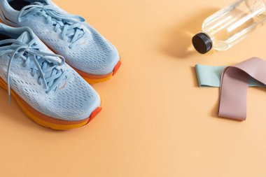 Açık turuncu arka planda spor ekipmanları ile düz yatıyordu