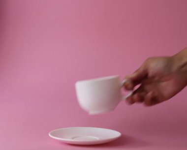 Bir kadın eli çay tabağına bir fincan koyar.