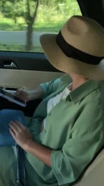 Hasır şapkalı genç bir kadın yolculuk sırasında arabada dans eder.