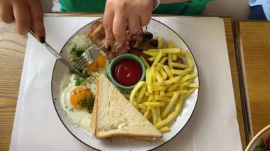 Yemek yiyor, genç bir kadın çırpılmış yumurta ve patates kızartması yiyor.