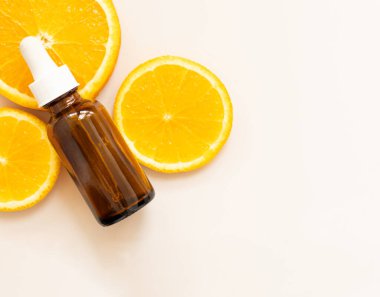 Yüz serumu C vitamini, portakal dilimleri, ambalaj kabı.