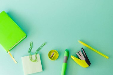 Düz döşeme, açık yeşil arka planda kırtasiye malzemesi, okula dönüş.