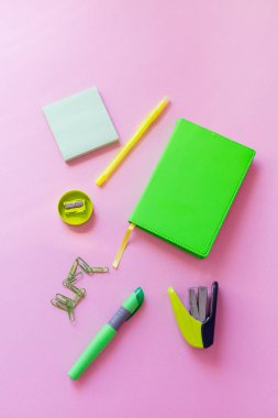 Pembe arka planda yeşil kırtasiye malzemesi, okula dönüş.
