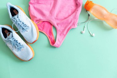 Açık yeşil zemin üzerinde spor ekipmanları ile düz yatıyordu