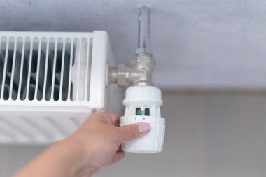 Bir kadının eli akü ısıtma düğmesini çevirir. Evde, bir dairede ısıtma. Isıtma fiyatları