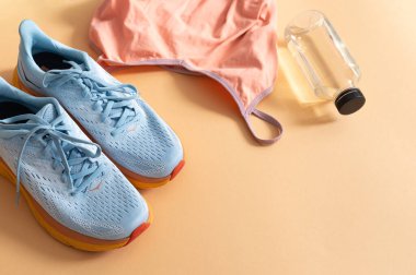 Spor kıyafetleri, ayakkabıları, kulaklığı ve beyaz arka planda bir şişe suyu olan bir daire.