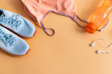 Spor kıyafetleri, ayakkabıları, kulaklığı ve beyaz arka planda bir şişe suyu olan bir daire.