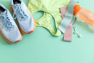 Spor giysileri, ayakkabıları, kulaklığı ve su şişesiyle yatıyordu.