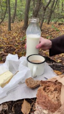Sonbahar ormanında piknik, açık havada kahve ve bardağa süt dökmek.