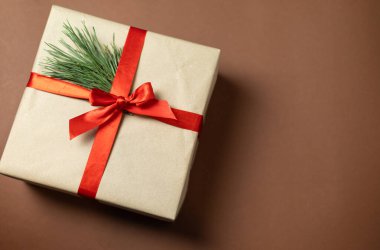 Kırmızı fiyonklu kraft kutusu ve Noel ağacı süslemesi.