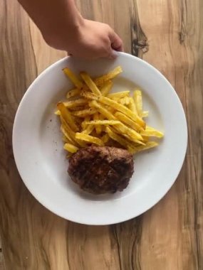 Masada patates kızartması ve pirzola ile kadın eli.