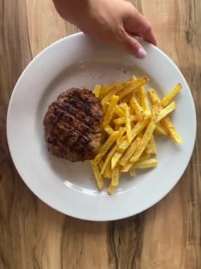 Masada patates kızartması ve pirzola ile kadın eli.