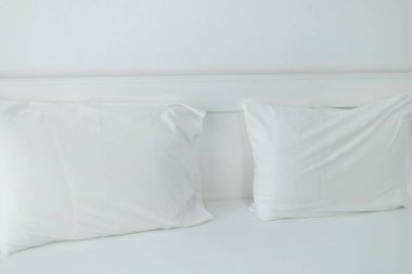Yatak başlığı, oteldeki beyaz bir yatakta yastıklar