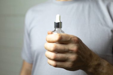 Bir adam elinde bir şişe serum tutuyor. Erkeğin bakımı