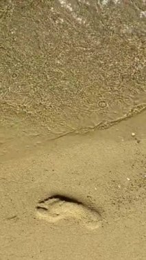 Deniz kenarındaki kumlu sahilde ayak izleri var.