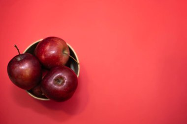 Kırmızı zemin üzerinde büyük bir kağıt bardak içinde olgun kırmızı elmalar.