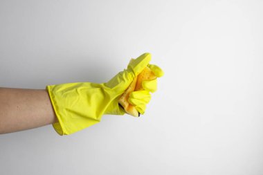 Temizlik konsepti. Sarı eldivenli bir el, temizlik için sarı bir sünger sıkar.