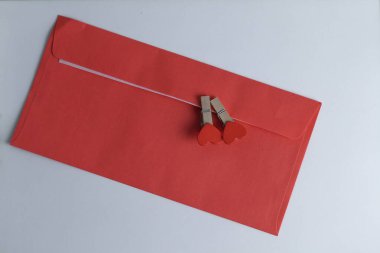 Üzerinde kırmızı kalpler olan küçük mandallı kırmızı zarf, kutlama konsepti.