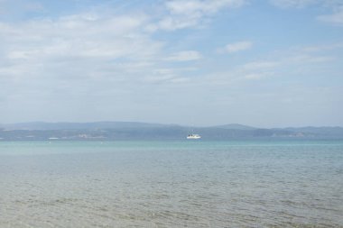 Ufukta bir deniz kenarında yelkenli.