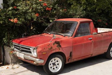 Çiçek açan ağacın altında kırmızı eski bir araba, paslanma ve paslanma.