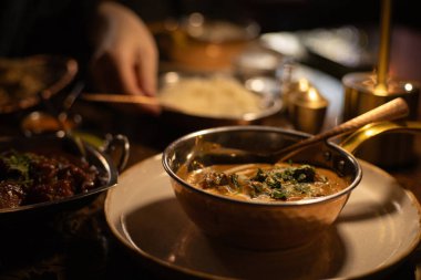 Hint yemeği tavuk körisi, arka planda bir adamın eli pirinç döküyor.